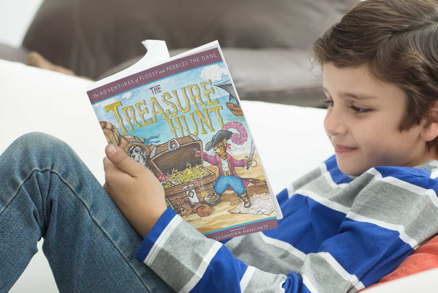 smiling young boy reading The Adventures of Flossy and Pebbles the Dane: The Treasure Hunt by Kimm Irwin