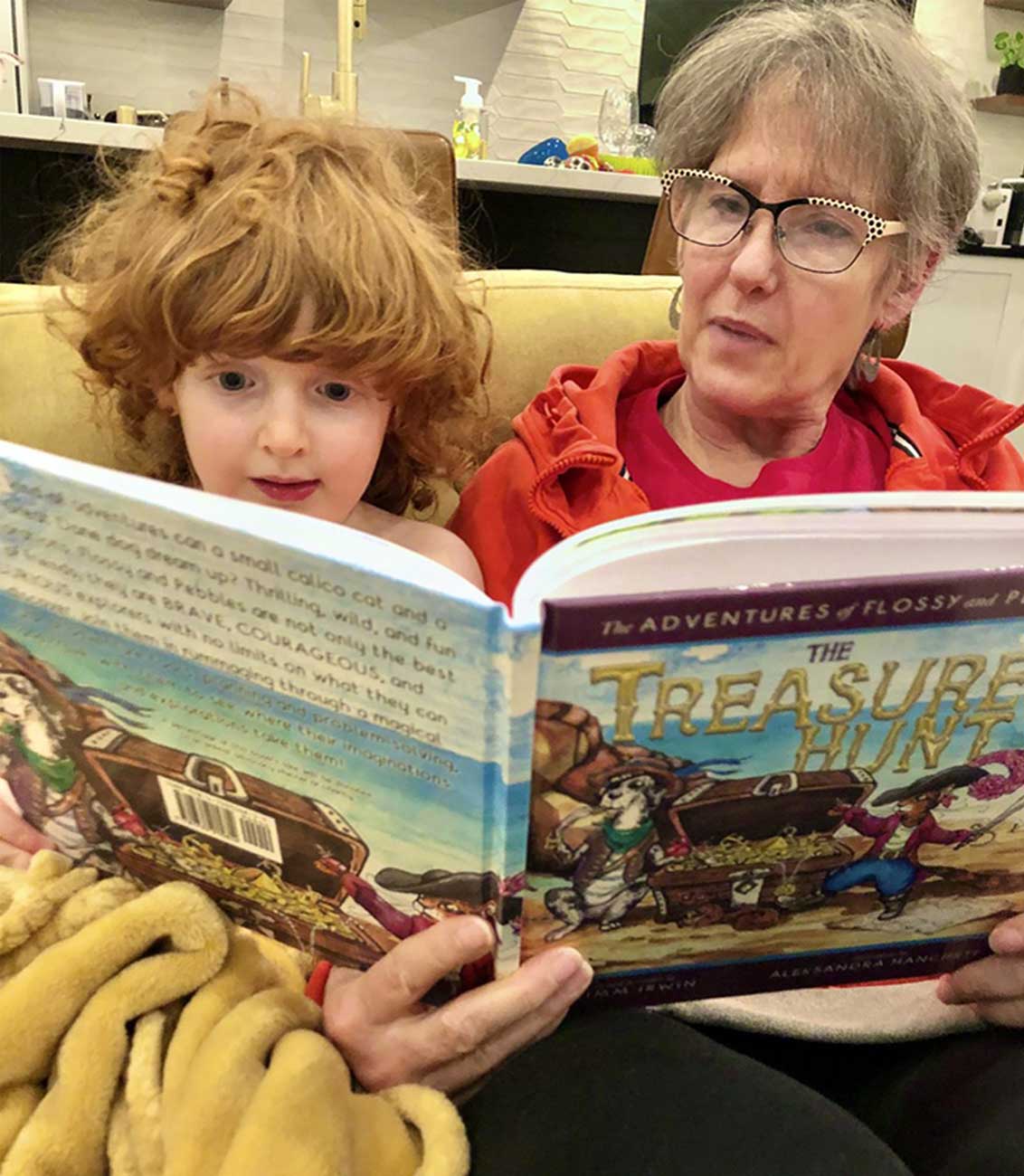 Archie and his grandma reading the children's book, The Adventures of Flossy and Pebbles the Dane: The Treasure Hunt