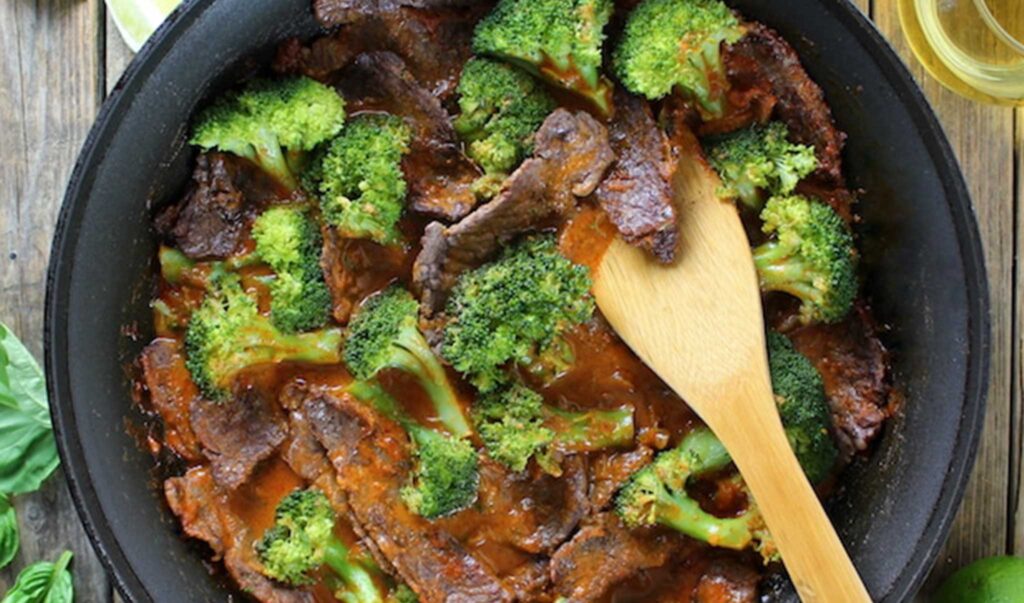 Thai beef and broccoli is pictured in a black skillet and is one of the international flavors on my list of easy, kid-friendly dinner recipes.