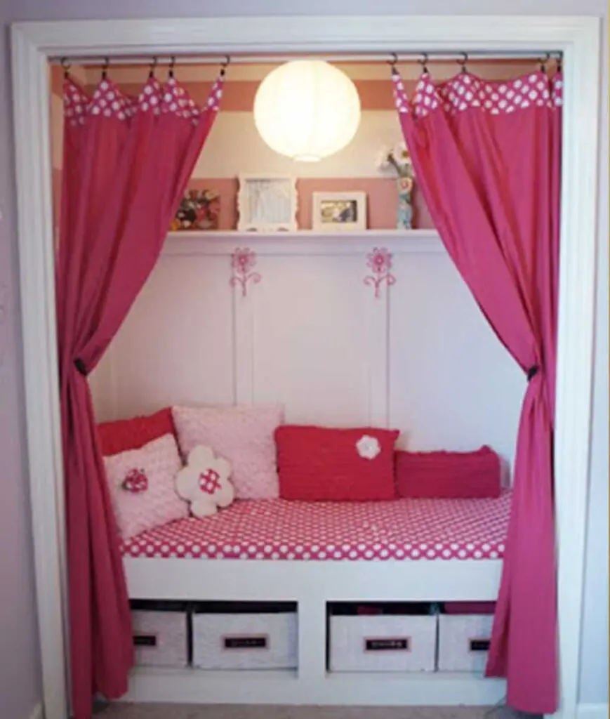 closet transformed into a reading nook using hot pink and white curtains, cushion, and throw pillows.