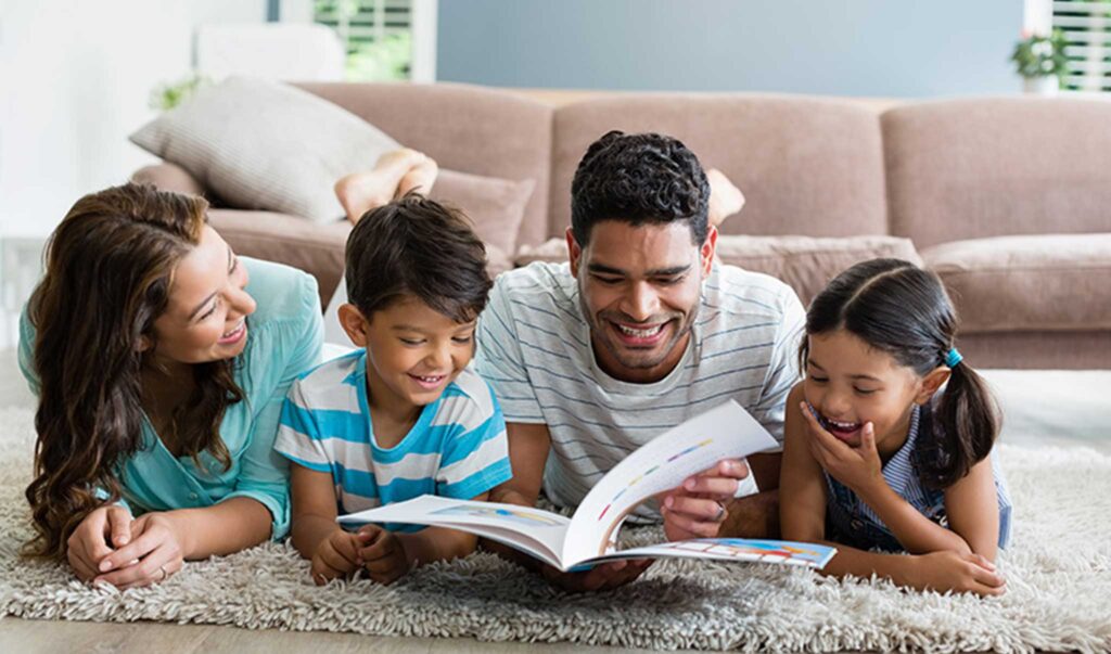 important benefits of reading to children represented by parents and young children reading together lying on a floor rug in their living room