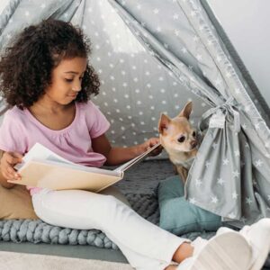 kids reading nook idea represented by a young girl reading in a cute indoor tent with her Chihuahua sitting next to her