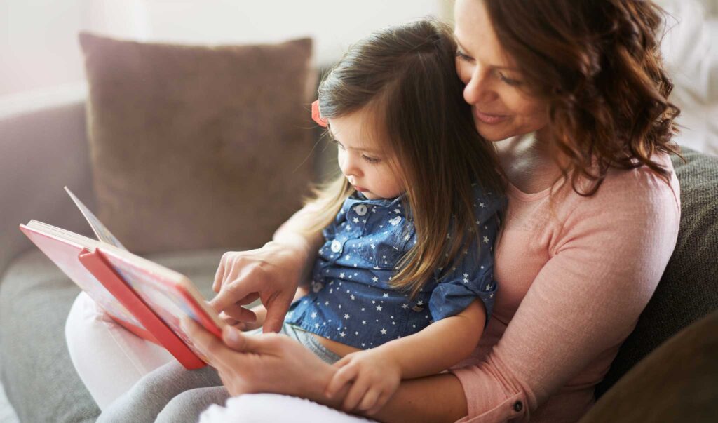 daughter sitting on mom's lap while she reads to her